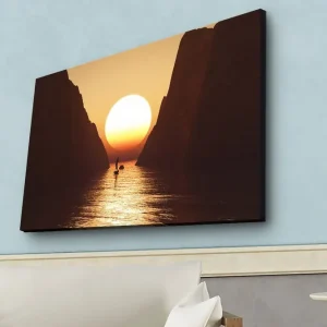 Canvastavla med LED-belysning - Storslagen solnedgång över en smal fjord med en segelbåt i silhuett Orange / Brun / Guld - Inredning Köp nu