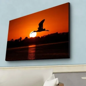 Säker betalning Canvastavla med LED-belysning - Silhuett av en fågel som flyger mot en solnedgång Orange / Svart - Inredning